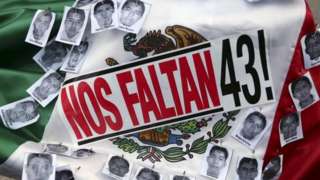 Pictures of the missing students of Ayotzinapa College Raul Isidro Burgos and a sticker that reads "We are missing 43", are seen over a Mexican flag during a march to mark the 16-month anniversary of their disappearance, in Mexico City, January 26, 2016.