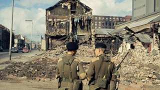 British soldiers look at a building damaged by a bomb during the Troubles in Northern Ireland