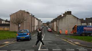 Refuse collectors work on a street in Workington, north west England on November 6, 2019