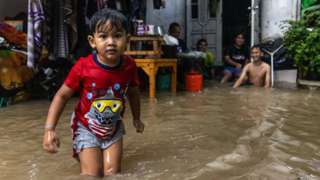 A boy walks through a submerged road in Thailand