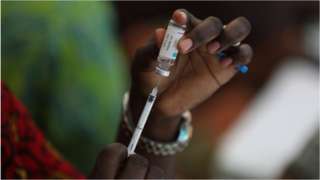 A health worker drawing vaccine from a vial