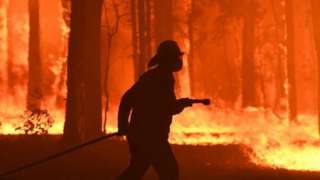 A firefighter silhouetted against a blaze