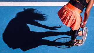 Japan’s Naomi Osaka removes a butterfly from her dress as she plays against Tunisia’s Ons Jabeur during their women’s singles match on day five of the Australian Open tennis tournament in Melbourne on 12 February 2021.