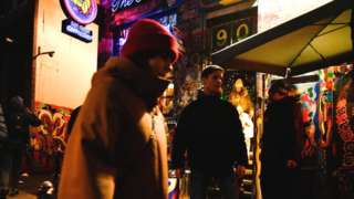 People walks near a Coffeeshop in Amsterdam's Red Light District