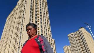 A woman walks in front of a housing complex by Chinese property developer Evergrande in Beijing