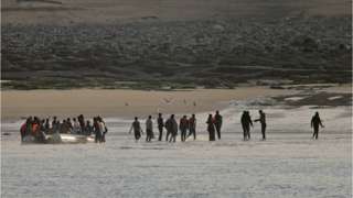 A group of migrants leave a dinghy after an unsuccessful attempt to cross the English Channel