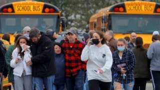 Parents walk away with their kids after the shooting at Oxford High School in Oxford, Michigan