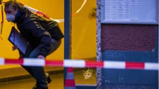 A policeman walks past a hole from a bullet in a window at a crime scene in Berlin's Kreuzberg district on December 26, 2020, following a shooting.
