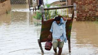 A man drags his belongings through flood waters in Balochistan in southern Pakistan