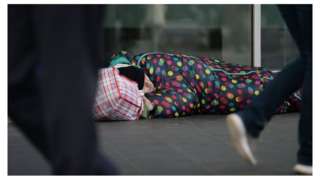 A man sleeping on the street in a sleeping bag