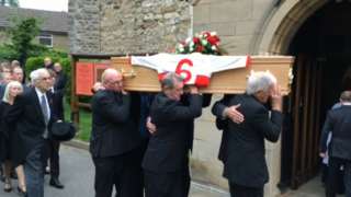 Pallbearers carrying Roger Millward's coffin into a church