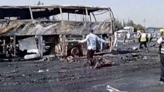 A man is seen running in front of a burnt out bus in Egypt