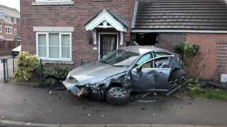 Smashed up car outside a house