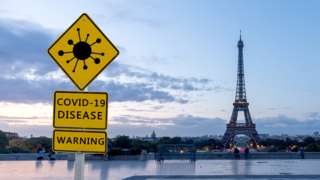 Picture of the Eiffel tower in Paris with a Covid sign in the foreground