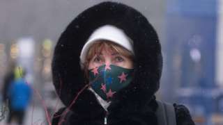 A woman visits Times Square as snow falls during a winter storm in New York