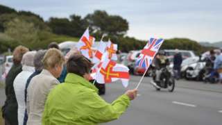 People waving Guernsey flags watching the Cavalcade