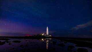 A lighthouse reflected in water at night time
