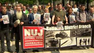Demonstrators in Belfast hold signs in protest against the journalists' killing