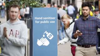 man uses a public hand sanitiser in Leeds city centre
