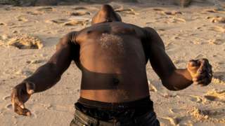 A man stretches before his workout along the coastline in Pemba on May 19, 2021. Pemba, the capital of Cabo Delgado has taken in tens of thousands of people fleeing from violence wreaked by Islamist insurgents across the northern province for over three years.