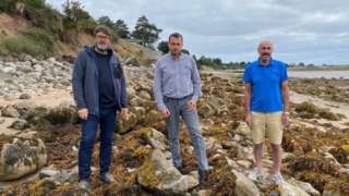 Councillors Carwyn Jones, Gary Pritchard and Alun Roberts on the beach