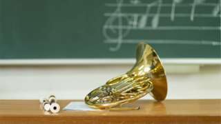 Instruments on school desk with notation on board behind