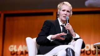 Photo of E Jean Carroll speaking into a microphone at a 2019 panel in New York City.