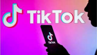 Person's silhouette in front of TikTok logo