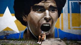 A woman cries in front of a mural of Diego Maradona, in Buenos Aires