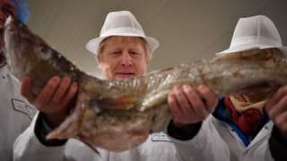 UK Prime Minister Boris Johnson holding a large fish