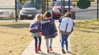 School children wearing facemasks walk outside Condit Elementary School in Bellaire, outside Houston, Texas