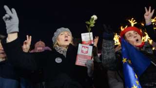 Polish protesters against a controversial new judicial reform law hold copies of the constitution and EU flags in Warsaw