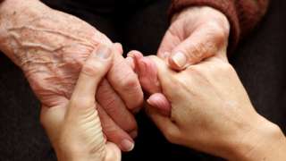 Old and young hands clasped together