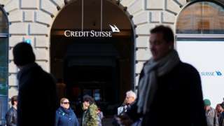 People walk near the logo of the Swiss bank Credit Suisse in Zurich, Switzerland March 20, 2023.