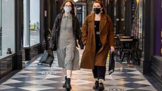 Two women walking through Cardiff wearing masks