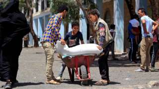 Yemenis receive humanitarian aid provided by the World Food Programme (WFP) in the Yemeni capital Sanaa