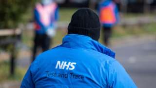 An NHS Test and Trace logo on a member of staff"s jacket