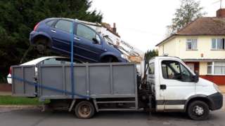 Van with cars strapped to trailer