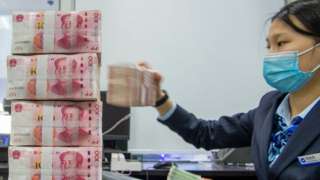 Banker worker counts Chinese currency notes.