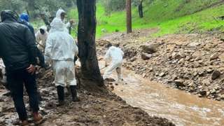 Volunteers digging trenches after giant boulders and mud blocked access to some homes in California