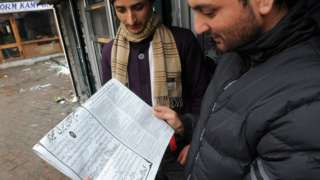Men reading a newspaper in Srinagar