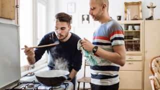 Two men cooking over a stove