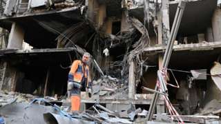 Рабочий разбирает завалы на месте разрушенного здания в Киеве