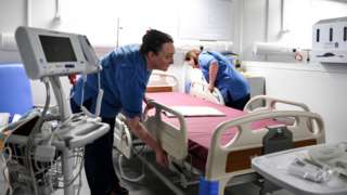 Nurses prepare bed in front of venilator