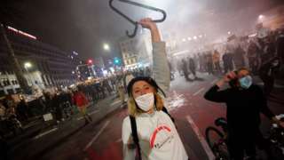 A woman holds coat hanger, a symbol of illegal abortions and women's suffering while shouting slogans in Warsaw, Poland on 26 October