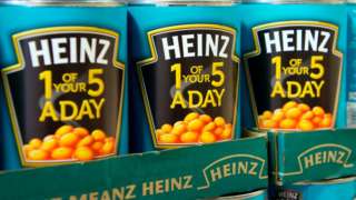Cans of Heinz baked beans on shop shelf.