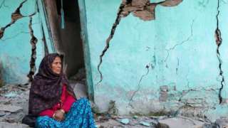 A woman sits beside a cracked wall of her house at Joshimath in Chamoli district of India's Uttarakhand state on January 10, 2023.