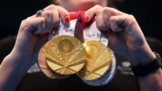 An athletes holds a clutch of Paralympic medals
