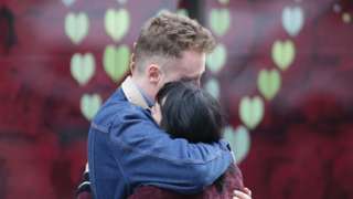Couple hug after leaving a bunch of flowers in tribute to the victims of the terror attack