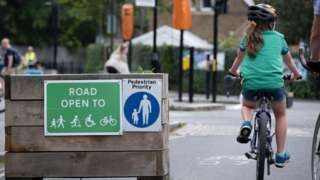 A young cyclist passes through the barriers that form an LTN (Low Traffic Neighbourhood),